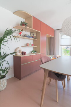 Wandmeubel van vloer tot plafond met roze fronten en  licht houten planken