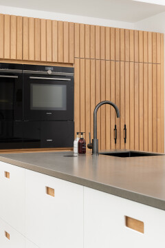 Close-up van donker werkblad gecombineerd met verticale eiken latten in keukenontwerp