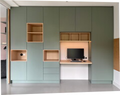 Groene maatwerk kastenwand in Castricum met groene fronten, open houten vakken en ge&iuml;ntegreerde werkplek met bureau en subtiele LED-verlichting in een rustig, modern interieur.