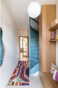 entree huis met blauwe trap en kleurrijk vloerkleed en maatwerk garderobe wandkast van hout