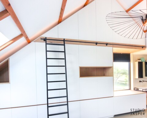 Royale maatwerkkast onder schuine kap met zwarte ladder in Lisse