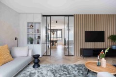 Stijlvolle woonkamer met grijze bank lattenwand met tv en trapombouw maatwerk kast