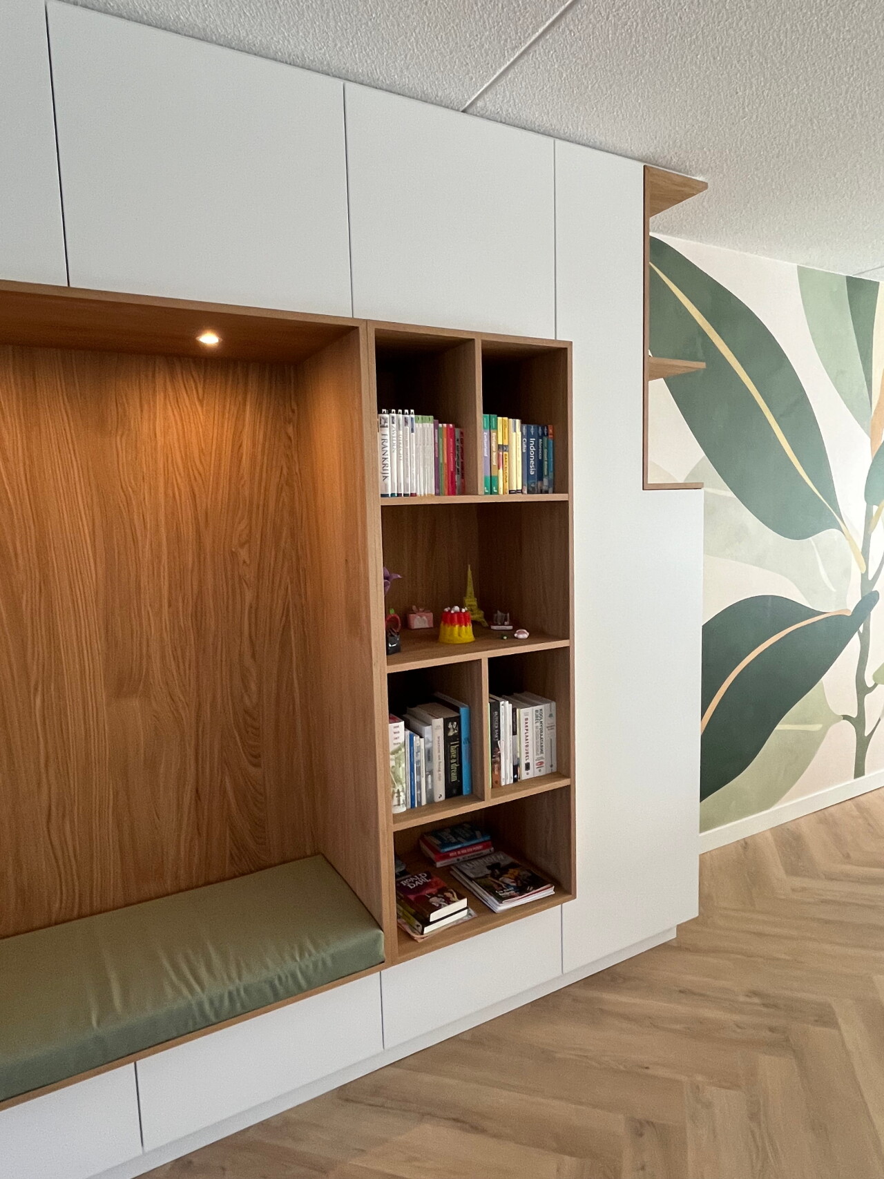 verlichte zitnis met groen kussen op maat en open vakken  waarin boeken staan