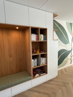verlichte zitnis met groen kussen op maat en open vakken  waarin boeken staan